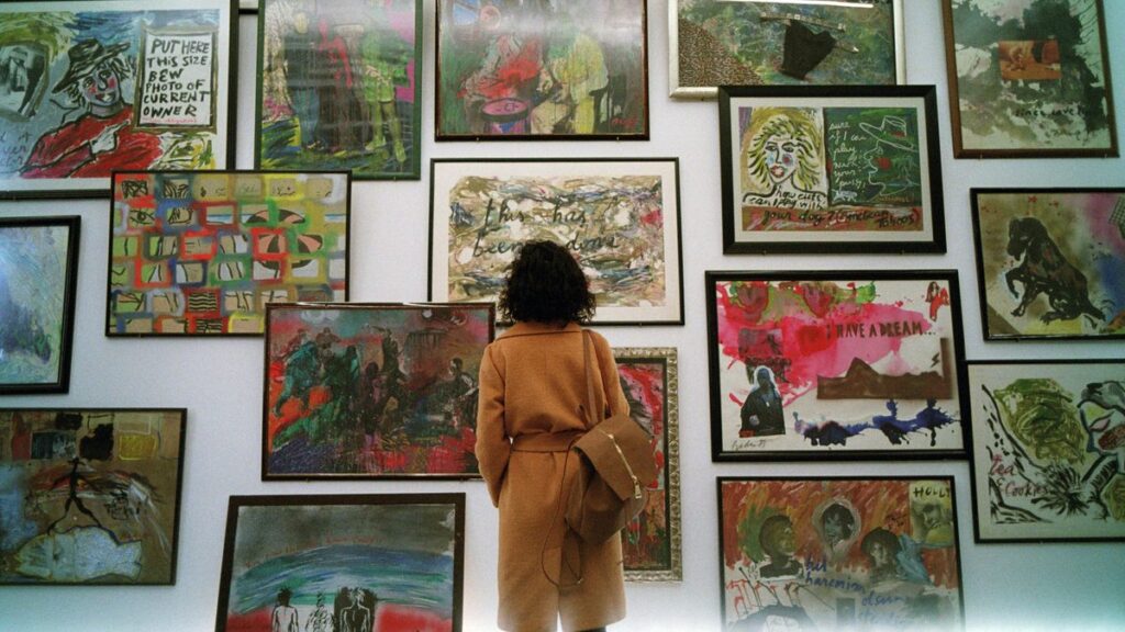 a woman standing in front of a wall covered in pictures